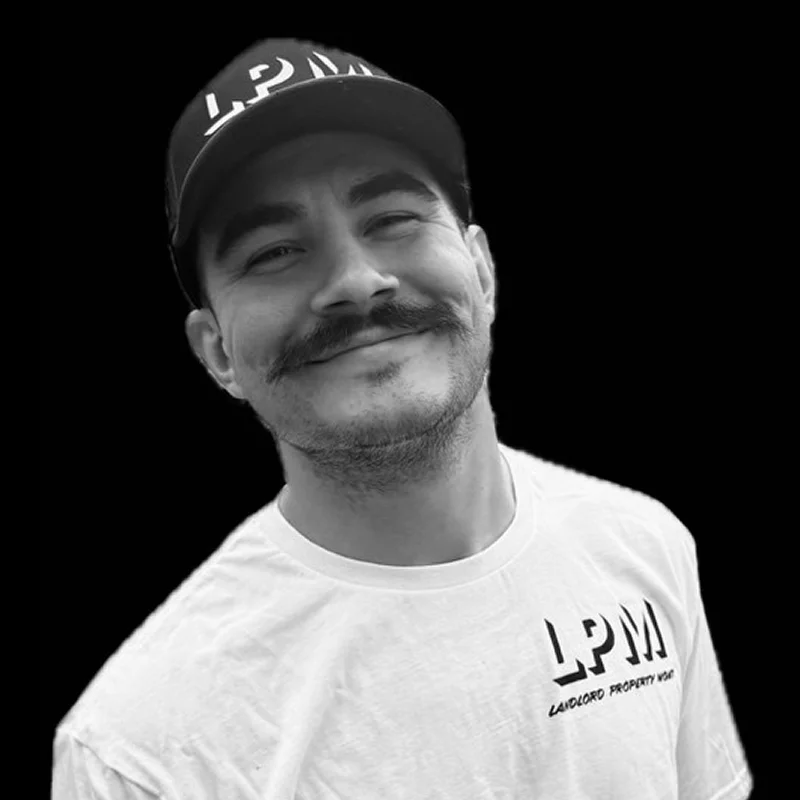 Smiling man with mustache wearing LPM cap