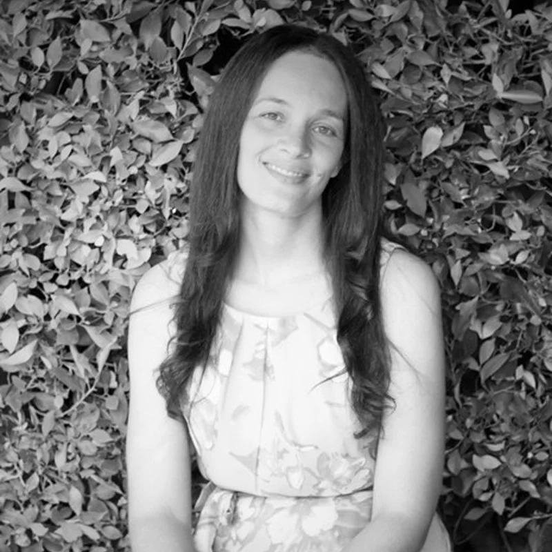 Smiling woman in floral dress by hedge